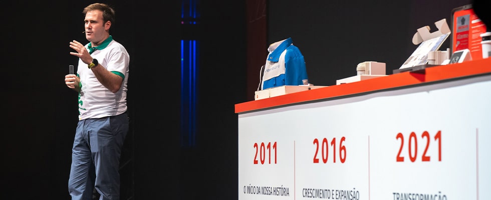 presenter on stage giving a talk beside a timeline display showing years 2011 2016 2021 and brief captions  youprotv